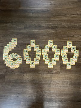 Mahjong tiles are arranged on a wooden floor to spell out the word "GOOO" next to a stylized soccer ball shape.