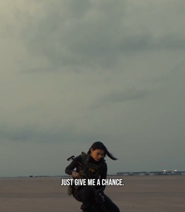 A woman in tactical gear holding a rifle against a beach/sky background with the subtitle text 'JUST GIVE ME A CHANCE.'