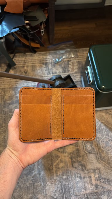 !!!IMAGE!!! This is an image that features a person's hand holding up a small leather wallet, which appears to be handmade or crafted with love by someone who has made it themselves. The wallet is brown and seems quite sturdy, suggesting it could be made of leather or other durable materials. The image also includes text in the caption, which reads "Another day of !!!XRP being down and me needing someone to buy a $95 made in the USA hand stitched wallet: dm me".