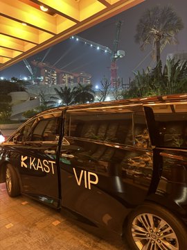 A black VIP van with "K KAST" and "VIP" lettering on its side, parked under an awning at night near a stadium.