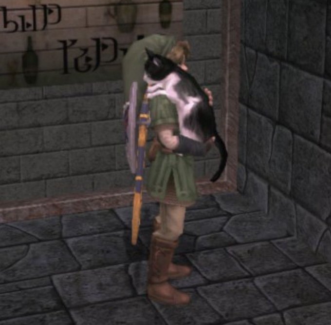 A low-resolution screenshot from an older video game showing a green-tunic character hugging a black and white cat in a stone corridor.