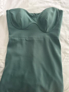 A custom-made teal green satin dress with a sweetheart neckline is laid flat on a white fabric surface, referencing the "Hyperliquid dress" mentioned in the post as a bespoke creation tailored in Dubai.