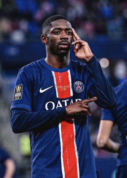 PSG forward Ousmane Dembélé, wearing the club's blue and red QATAR-sponsored jersey with the Ligue 1 patch, gestures with his hand to his temple while looking off into the distance—fittingly capturing a moment of rest or reflection as he prepares to sit out his second match of the season against Le Mans on Saturday.