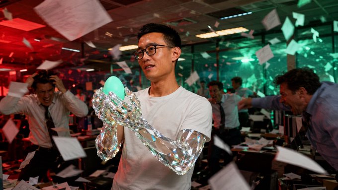 A young man in glasses and a t-shirt, with his arm wrapped in tin foil, carefully cradles a glowing green egg amid a chaotic office scene where traders frantically swat at flying papers. The image serves as a visual metaphor for the post's commentary on Hyperliquid traders: while everyone else scrambles in a frenzy chasing the next "meta," the man calmly holds "the most coded egg that never moved," symbolizing steady conviction amid market chaos.
