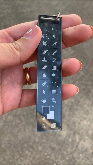 A hand holds a clear acrylic bookmark featuring a column of digital design tool icons.