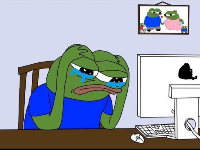 A cartoon image of a sad green frog-like character crying at a computer desk.