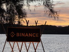A Binance-branded director's chair sits by the water at sunset, capturing the relaxed luxury of the Binance VIP Phuket Retreat referenced in the post. The branded chair visually anchors the caption, symbolizing the event's premium, exclusive atmosphere.
