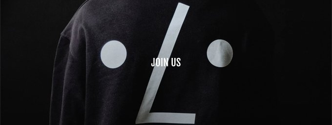 A black sweatshirt featuring a minimalist face design made of two white circles and a white line, with the text "JOIN US" across the center.