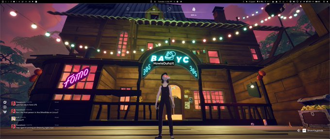 A screenshot from a VR environment (likely VRChat) showing a virtual avatar standing in front of a wooden building with neon signs reading "HomeisOchuhi" and "FoMo", with a chat window visible on the left.