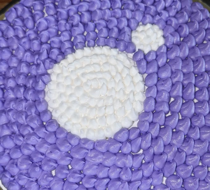 A close-up of purple and white candies/pearls arranged to form an Apple logo.
