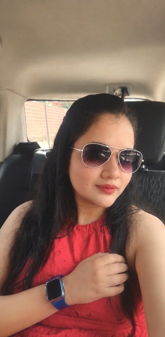 A woman with long black hair, wearing aviator sunglasses and a red top, poses for a selfie inside a car while sporting a blue-banded smartwatch.

The image shows her casually capturing the moment, fitting the post's theme of juggling multiple interests and daily life distractions like shopping, travel, and leisure activities.
