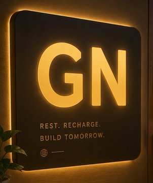 The image features a black square sign with white letters that reads "GN" at the top, accompanied by a motivational quote about rest, recharge, build, and tomorrow. The sign is placed against a wall or a door frame, possibly in an office setting. There are also some plants visible in the background, adding a touch of greenery to the scene.