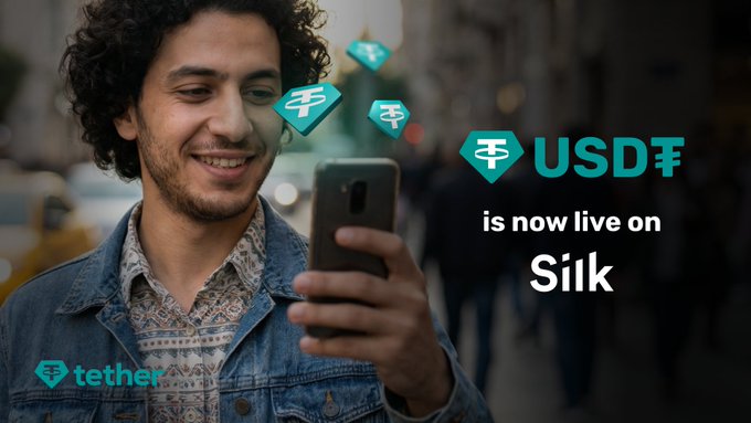 A smiling young man looks at his smartphone on a city street, with USDT (Tether) logos floating nearby and text reading "USD₮ is now live on Silk," advertising Tether's integration with Silk Bank Georgia.