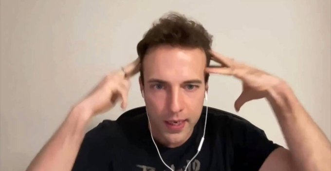 A man with earbuds holds his fingers to his temples in a gesture indicating focus or concentration.