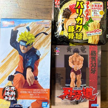 A collection of Bandai Namco merchandise, including a Naruto figure of "HIROKI AKIMOTO," a Baki "範馬刃牙" figure, and a packaged instant noodle product with Japanese text.