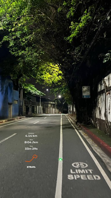 A nighttime view of a tree-lined road with a '25 LIMIT SPEED' marking, overlaid with a Strava running summary showing 4.14 km at an 8:04/km pace in 33m 29s.