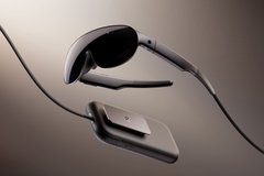 A sleek, minimalist 3D render or image of futuristic smart glasses/sunglasses with thin metal arms and black lenses, photographed against a dark gradient background.