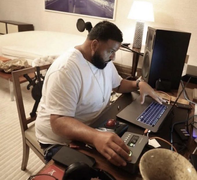 A man sits focused at a desk working on a laptop surrounded by audio equipment and recording gear, looking intently concentrated. The image humorously matches the post's sentiment, depicting him using his full mental focus to navigate complex financial concepts like interest rates and regulatory clarity affecting cryptocurrency, evoking the "hunting and gathering" mindset applied to modern digital finance.