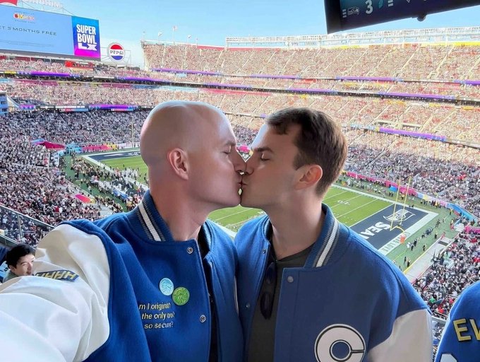 Two men in blue Colts jackets kiss at what appears to be Super Bowl LVI in a packed stadium, with Pepsi and "SUPER BOWL LVI" signage visible above the field. The caption "I WARNED YOU You really trusted this guy?" humorously suggests the playful kiss was an unexpected outcome of a friendly challenge between the two.