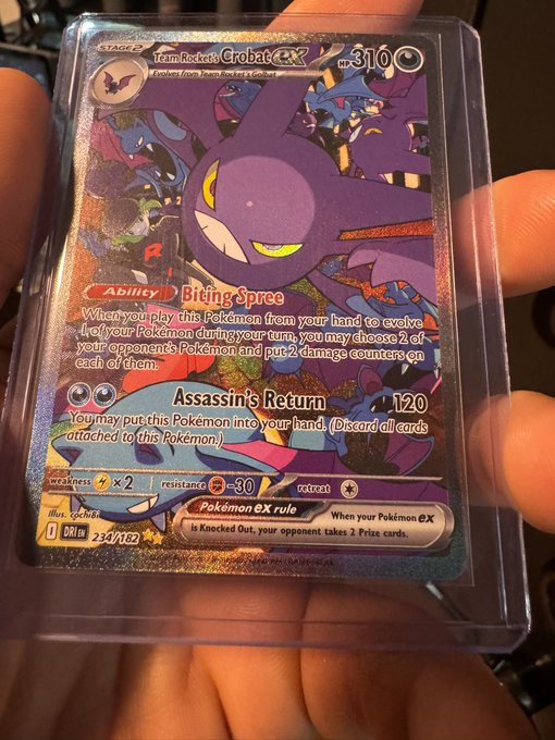 A hand holding a Pokémon trading card for 'Team Rocket's Grobat ex' (310 HP) from the Destined Rivals set, featuring holographic artwork and details.
