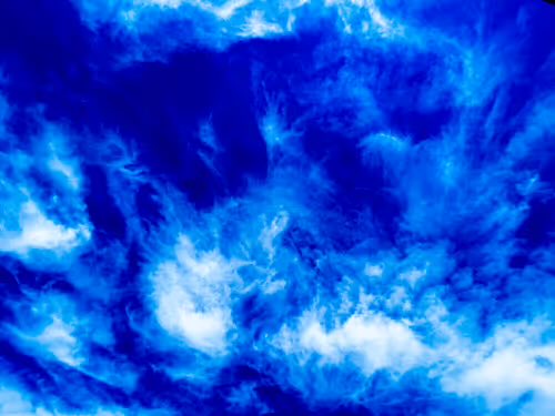 An abstract image showing swirling blue and white cloud-like or smoke-like patterns with varying shades of blue creating a textured, atmospheric effect.