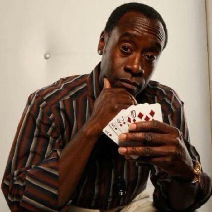 A man in a striped shirt looks thoughtfully at a hand of playing cards (King, Queen, Jack, 10), appearing contemplative about his next move.