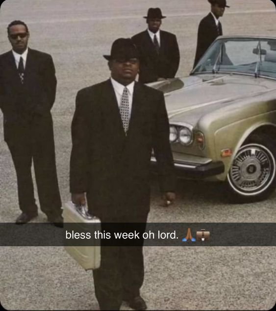 Men in black suits and hats standing next to a luxury car, with a caption reading "bless this week oh lord. 🙏🪨".