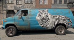 The image shows a van painted with a large, striking mural of a white tiger against a blue background, parked on a city street. It connects to the post by serving as a vivid visual metaphor for the "Razor Wallet" meme—the tiger's fierce, predatory presence echoing the sharp, dangerous nature implied by a wallet "made of literal razors," while the "FLUX 3." caption appears to be a unrelated tag attached to the post.