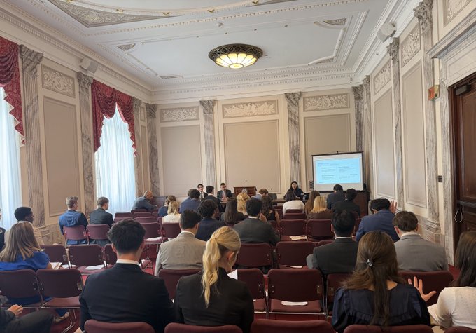 Attendees gather in an ornate government chamber for a congressional briefing on DeFi, with a presentation displayed on screen as speakers address the audience from the front.