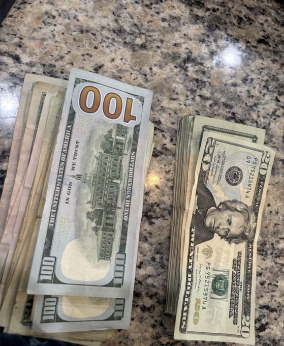 Two stacks of U.S. currency sit on a granite countertop—one stack of $100 bills and another of $20 bills—visually contrasting wealth against the question of whether a strong reputation outweighs financial riches.