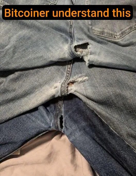 A pair of worn blue jeans is shown with several torn and frayed holes in the crotch and upper thigh area, with the text 'Bitcoiner understand this' overlaid at the top.