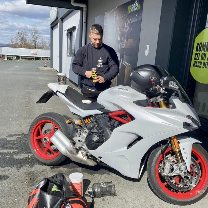 A man stands beside his old white and red Ducati sportbike, fueling it up before a ride. The image evokes nostalgia for a cherished possession he once owned, connecting to his reflection on selling the bike to fund his early business ventures.