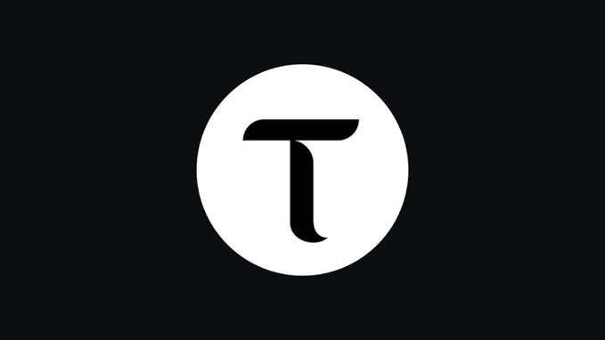 A minimalist logo featuring a bold serif letter "T" centered within a white circle on a dark background, visually anchoring the $TAO cryptocurrency ticker discussed in the accompanying technical analysis post about the asset's symmetrical triangle pattern and key price levels.