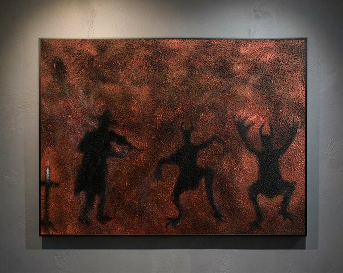 A framed painting displayed on a wall depicting silhouettes of a cowboy with a gun, a horned demon, and a frog-like creature against a fiery red textured background.