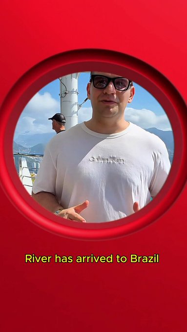 A man wearing sunglasses and a Calvin Klein white t-shirt poses on what appears to be a boat or platform, viewed through a circular red frame. The caption reads 'River has arrived to Brazil'.
