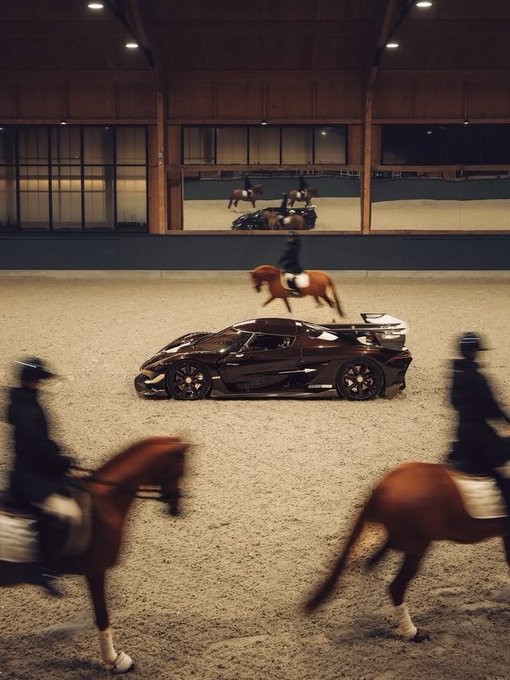 A Bugatti hypercar parked in an indoor equestrian arena with riders on horses passing by in the foreground, including a backdrop showing a horse and rider scene.