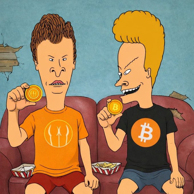 A Beavis and Butt-Head style cartoon shows two characters on a couch holding Bitcoin-themed tokens and apparel.