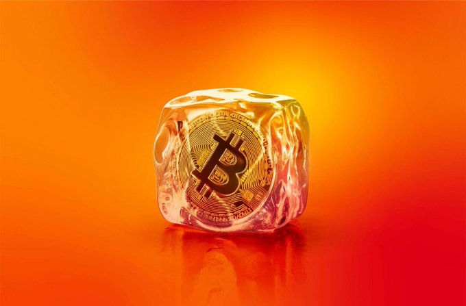 A golden Bitcoin coin encased in a translucent ice cube against a vibrant orange background.