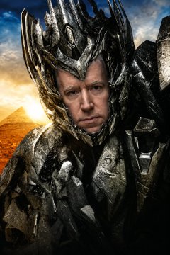A man wearing elaborate spiked armor and a horned helmet stands against a fiery, apocalyptic backdrop.