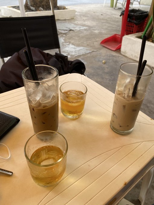 A photo of a table with three glasses of iced beverages and black straws at what appears to be an outdoor cafe.