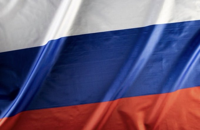 A close-up of a fabric displaying the white, blue, and red horizontal stripes of the Russian flag.