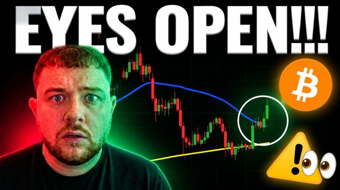 A shocked-looking man is featured on a YouTube thumbnail with bold "EYES OPEN!!!" text, alongside a Bitcoin candlestick chart showing price action with a circled breakout area, a Bitcoin logo, and a warning emoji with googly eyes. The thumbnail visually reinforces the video's alarmist caption about Bitcoin, using the surprised expression and warning symbols to convey urgency about potential price movement.
