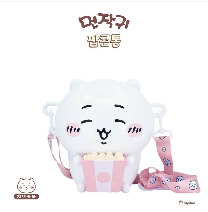 A plush character-shaped popcorn bucket from the Korean franchise "먼작귀" (Chiikawa), featuring a cute white bear-like figure holding a pink striped popcorn container, with Korean text "팝콘통" (Popcorn Bucket) and the "치이카와" (Chiikawa) logo displayed alongside an adjustable pink patterned strap for carrying.