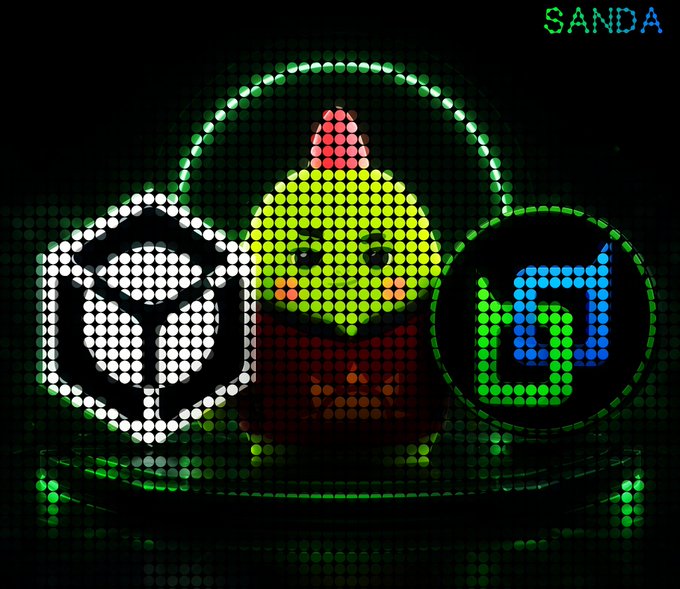 The image displays a pixelated graphic featuring a cartoon figure with yellow skin and a party hat, surrounded by green glowing circles and the logos "B" (Beldex) and "id" (Nucleus), with "SANDA" text visible at the top right. The illustration visually represents the Nucleus platform campaigns for Beldex Coin and Sleepagotchi mentioned in the post, highlighting the rewards opportunity for content contributors.