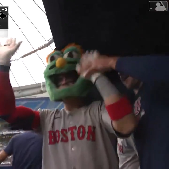 The image features a baseball player wearing a Boston Red Sox jersey, standing next to another player who has his arms raised high above his head. Both players are smiling for the camera, creating an atmosphere of excitement and camaraderie within the team. The photo captures this moment in time, showcasing the bond between teammates and their shared passion for the sport.