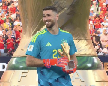 Spanish goalkeeper Unai Simón (jersey #23) smiles while holding the Golden Glove trophy after the 2022 FIFA World Cup final.