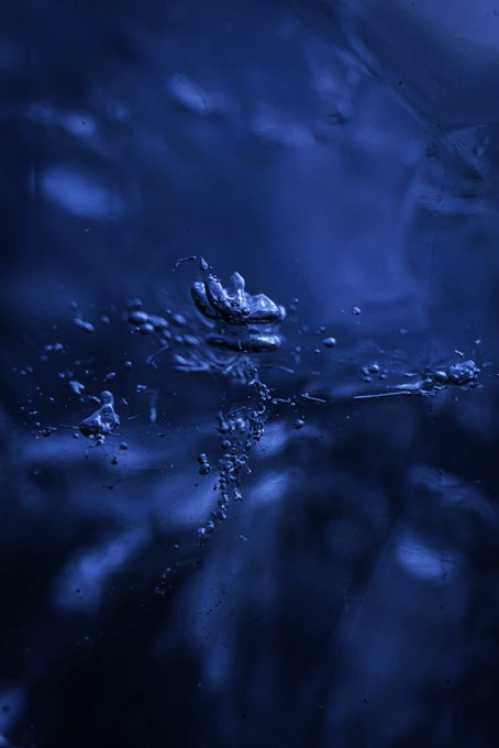 A dark blue abstract image shows water droplets suspended mid-splash, capturing a dynamic moment of liquid motion.