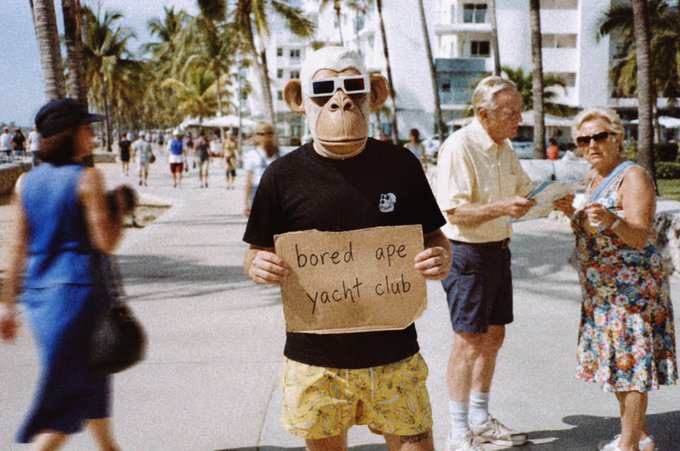 The image features a man wearing sunglasses, a monkey mask, and holding up a sign that reads "bored ape yacht club". He appears to be standing on a sidewalk or street with palm trees nearby. In the background, there are other people walking around, including one person who is carrying a handbag. The post about the "GM bored ape yacht club" seems to be related to this scene as it might be an advertisement for a themed event or gathering involving monkeys and yachts.

The man in the monkey mask and sunglasses holding up the sign adds a humorous and quirky element to the image, making it more interesting and engaging for viewers. The presence of palm trees also suggests that the location could be near a beach or coastal area where such events might take place.