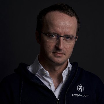 A portrait of Crypto.com CEO Kris Marszalek, wearing a dark branded jacket featuring the Crypto.com logo and hexagon emblem, looking directly at the camera. The image accompanies news about his company's OG.com receiving SEC authorization to offer U.S. single-stock futures.