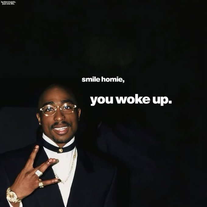 A photo of Tupac Shakur smiling and gesturing, with the text 'smile homie, you woke up.' and a small caption in the corner reading 'hedatarealtok: just one life.'